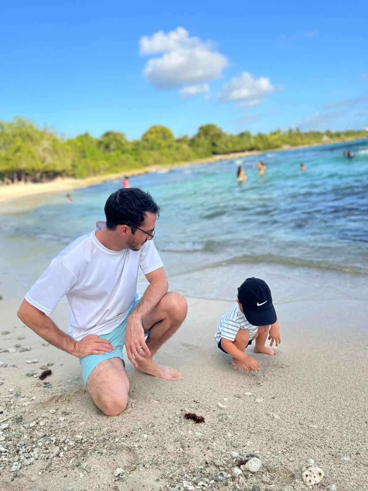 Kinder spielen im seichten türkisfarbenen Wasser an einem Strand in Bayahibe, Dominikanische Republik